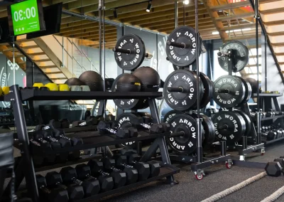 Strength training area at Shred Shed gym featuring racks of dumbbells, barbells, weight plates, battle ropes and workout equipment.